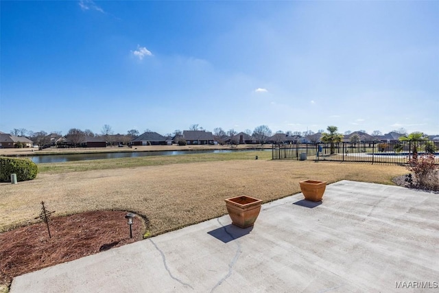 view of yard featuring a residential view, a water view, fence, and a patio