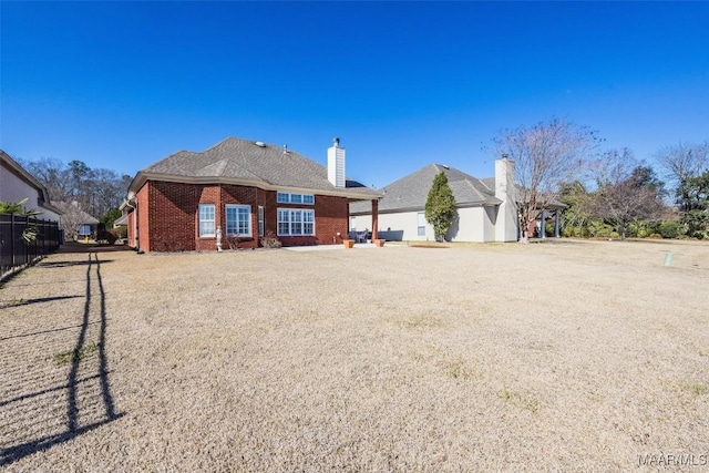 rear view of property with fence and brick siding