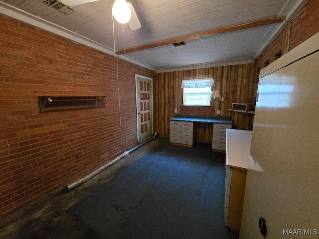 unfurnished office featuring brick wall, visible vents, dark colored carpet, and built in desk