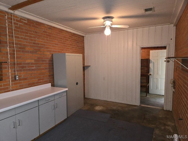 interior space featuring concrete flooring, brick wall, ceiling fan, and visible vents