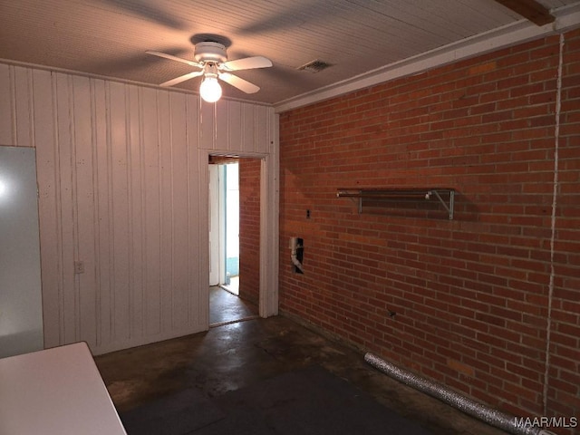 interior space with a ceiling fan, brick wall, visible vents, and concrete flooring