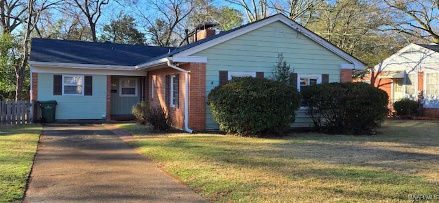 view of front of home with roof with shingles, a chimney, a front lawn, and brick siding