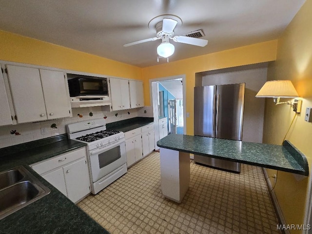 kitchen with dark countertops, white cabinets, and white gas stove