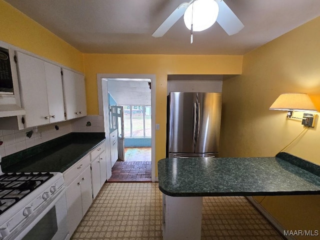 kitchen featuring dark countertops, white cabinets, and freestanding refrigerator