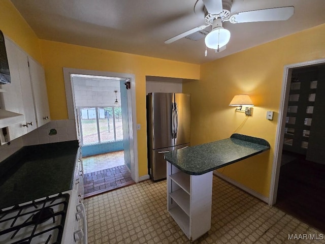 kitchen featuring a peninsula, white cabinets, freestanding refrigerator, open shelves, and dark countertops