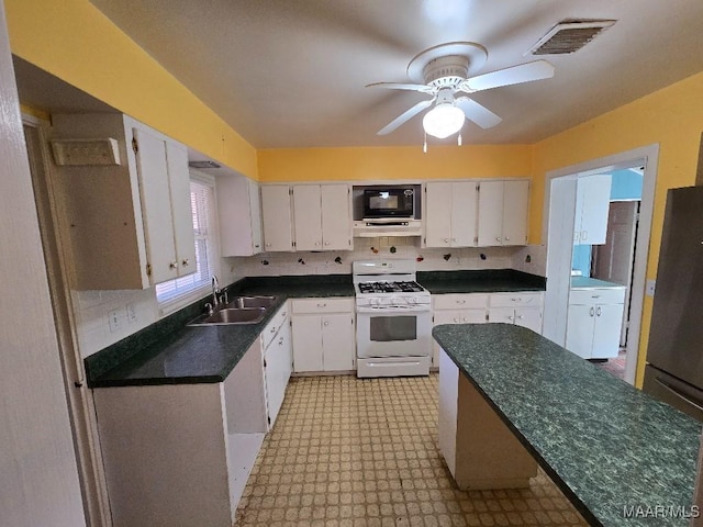 kitchen with gas range gas stove, dark countertops, visible vents, white cabinets, and a sink