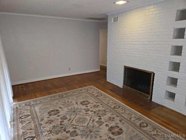 unfurnished living room with a brick fireplace, dark wood-style floors, visible vents, and crown molding