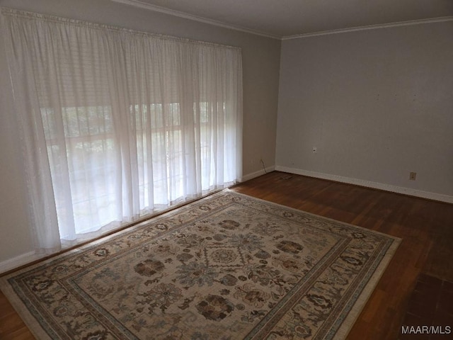 spare room with dark wood-style floors, baseboards, and crown molding