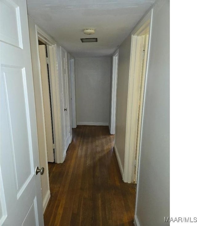 hall with dark wood-type flooring and baseboards