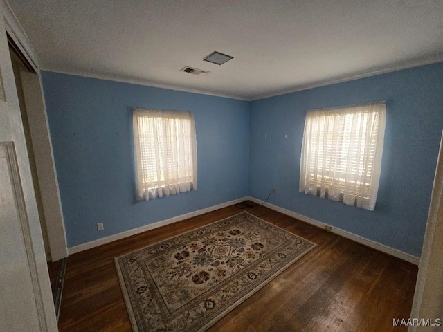 unfurnished room with visible vents, dark wood-type flooring, and a wealth of natural light