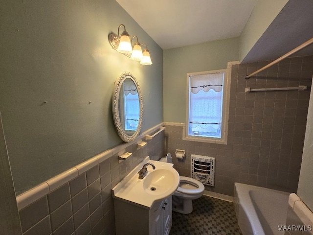 full bathroom with a bathtub, tile walls, heating unit, wainscoting, and vanity