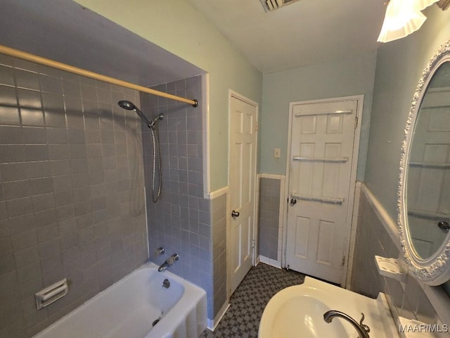 bathroom with shower / bath combination, a wainscoted wall, and tile walls