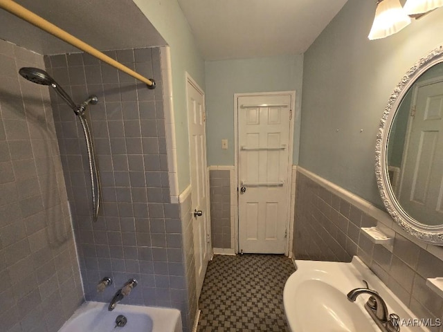 full bath featuring a wainscoted wall, a sink, washtub / shower combination, and tile walls