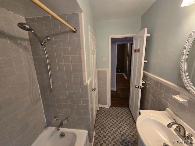 full bath featuring a sink, shower / washtub combination, tile walls, and wainscoting