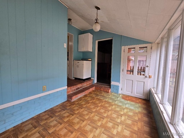 empty room featuring wood walls and vaulted ceiling