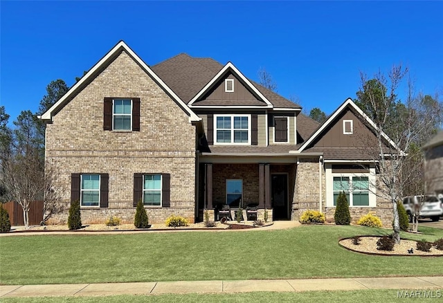 craftsman house with brick siding, a front lawn, and roof with shingles