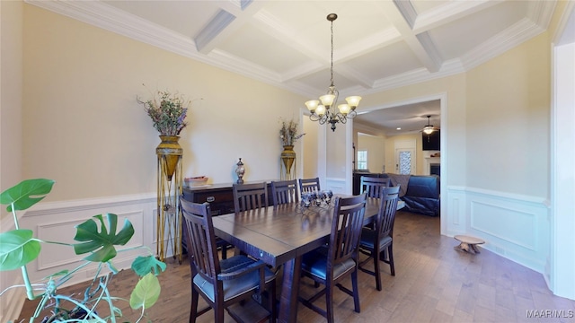 dining space with coffered ceiling, beamed ceiling, wood finished floors, a fireplace, and a notable chandelier