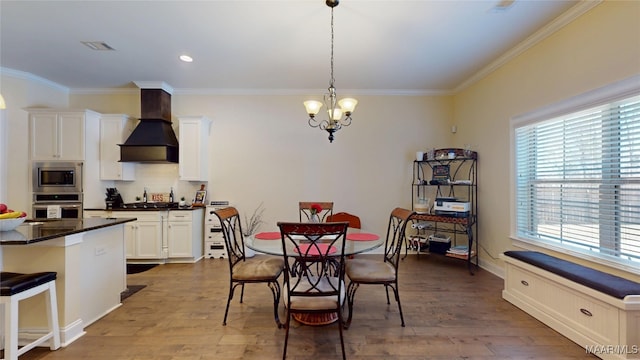 dining room with visible vents, ornamental molding, a notable chandelier, and wood finished floors