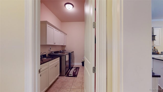 laundry room with light tile patterned floors, a sink, baseboards, cabinet space, and washer and clothes dryer