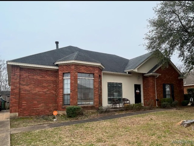 view of front of home featuring brick siding, a front lawn, and stucco siding