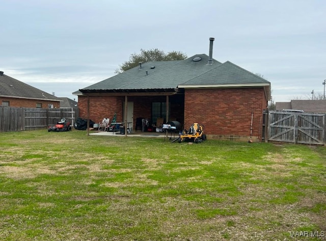 rear view of property featuring a patio area, brick siding, a yard, and a fenced backyard