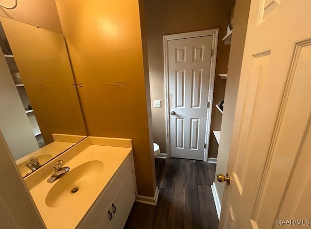 bathroom featuring toilet, wood finished floors, vanity, and baseboards