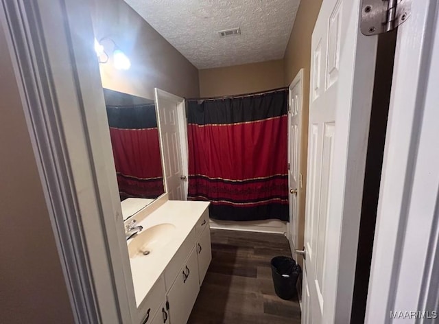 bathroom with curtained shower, visible vents, a textured ceiling, vanity, and wood finished floors