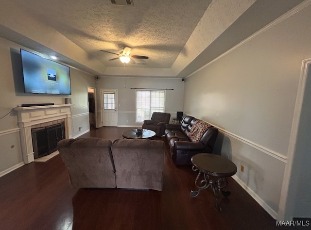 living area featuring a fireplace with flush hearth, a textured ceiling, a raised ceiling, and wood finished floors