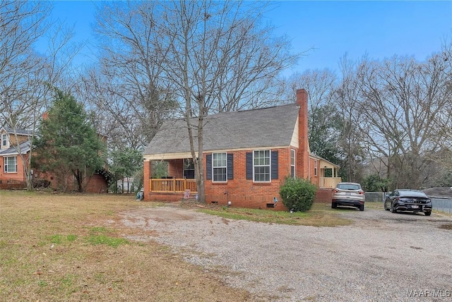 view of front of home with driveway, a chimney, crawl space, a porch, and brick siding