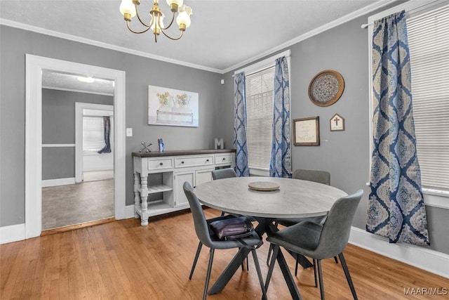 dining area featuring light wood-style flooring, ornamental molding, and a notable chandelier