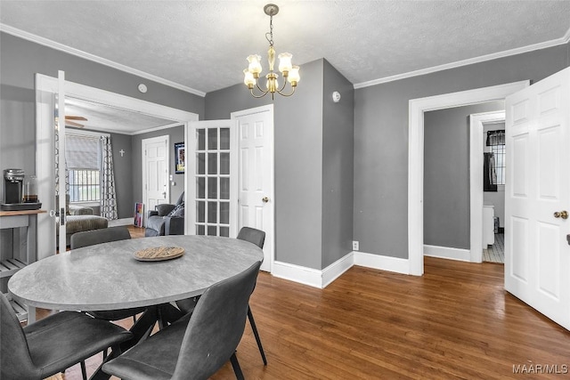 dining room featuring baseboards, ornamental molding, dark wood-type flooring, a textured ceiling, and a chandelier