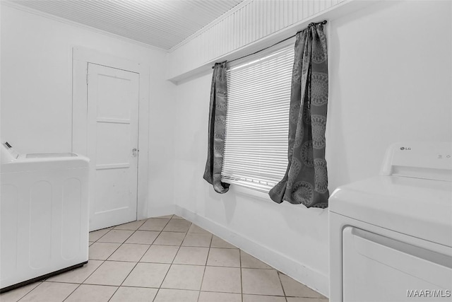 interior space featuring laundry area, baseboards, washer and dryer, and light tile patterned flooring