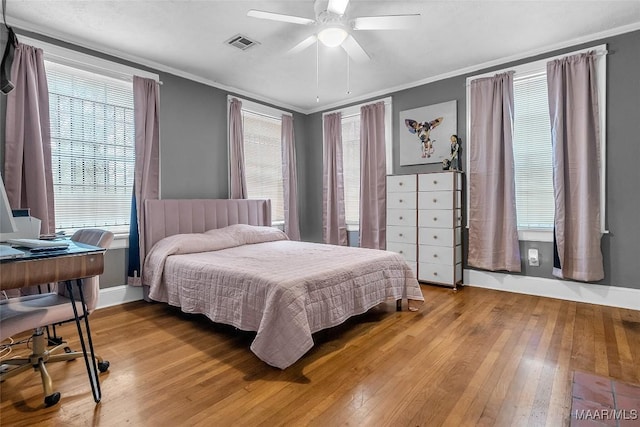 bedroom featuring baseboards, light wood-style flooring, visible vents, and crown molding