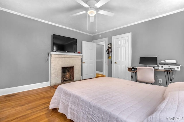 bedroom featuring crown molding, a ceiling fan, a brick fireplace, light wood-type flooring, and baseboards