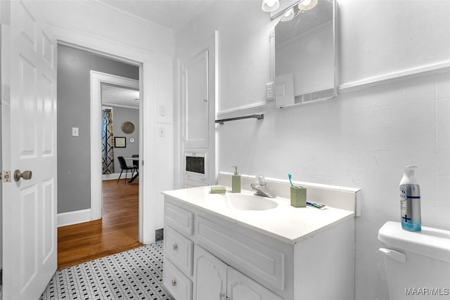 bathroom featuring tile walls, crown molding, vanity, and toilet