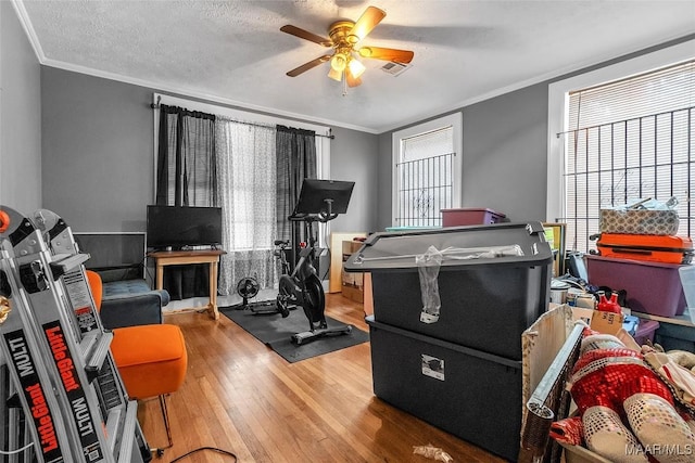 rec room featuring a ceiling fan, visible vents, ornamental molding, and hardwood / wood-style floors