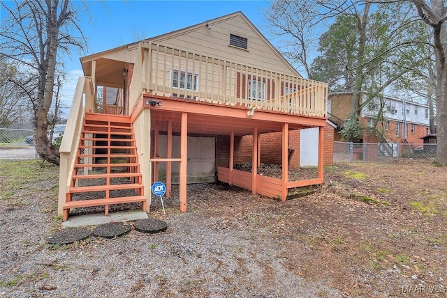 rear view of house with a deck, brick siding, fence, and stairway