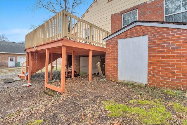 back of property with brick siding, a wooden deck, and stairs