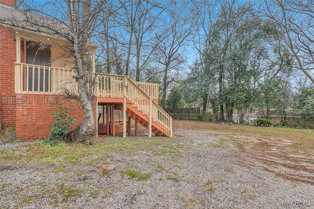 view of yard with fence, a wooden deck, and stairs