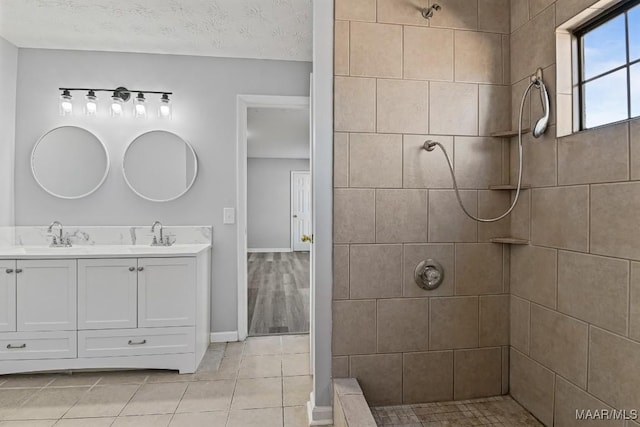 full bath with tile patterned flooring, tiled shower, a sink, and double vanity