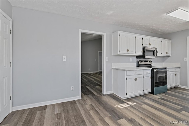 kitchen with baseboards, white cabinets, appliances with stainless steel finishes, wood finished floors, and light countertops