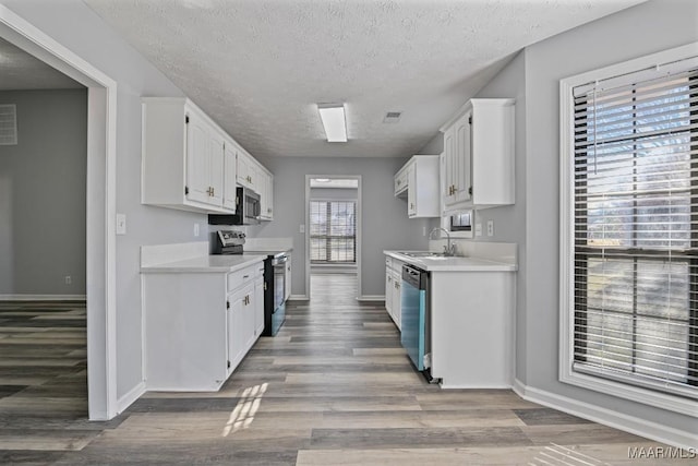 kitchen featuring visible vents, appliances with stainless steel finishes, light countertops, white cabinetry, and a sink