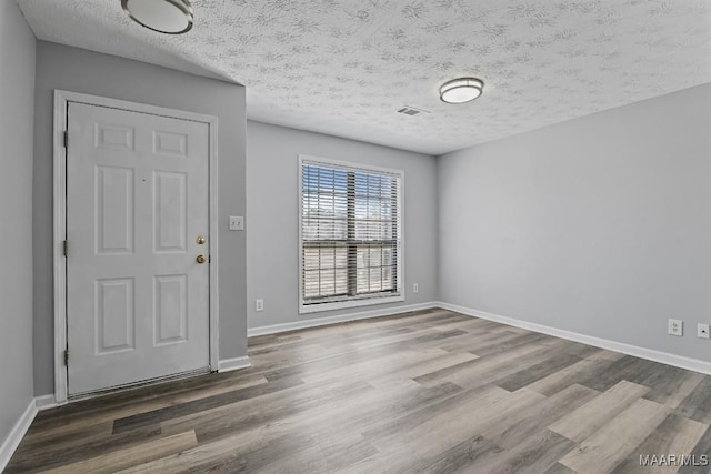 foyer featuring a textured ceiling, baseboards, and wood finished floors