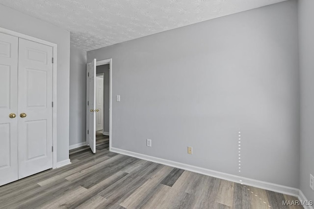 unfurnished bedroom featuring a closet, wood finished floors, and baseboards