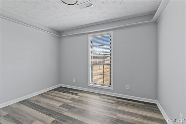 unfurnished room with baseboards, a textured ceiling, visible vents, and wood finished floors