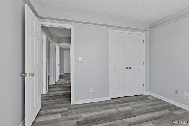 unfurnished bedroom featuring attic access, baseboards, and wood finished floors