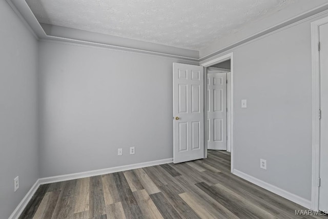 empty room featuring a textured ceiling, baseboards, and wood finished floors