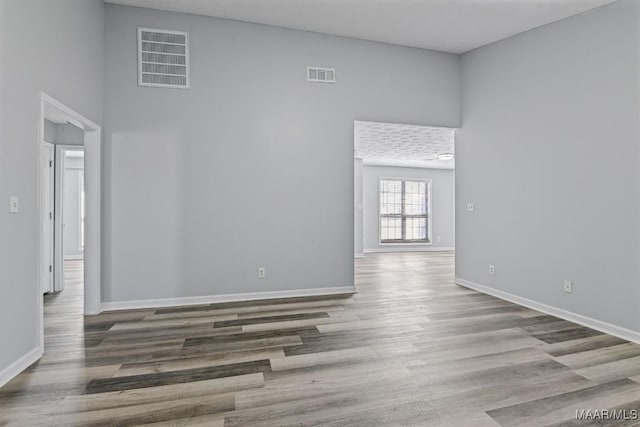 spare room with wood finished floors, visible vents, and baseboards