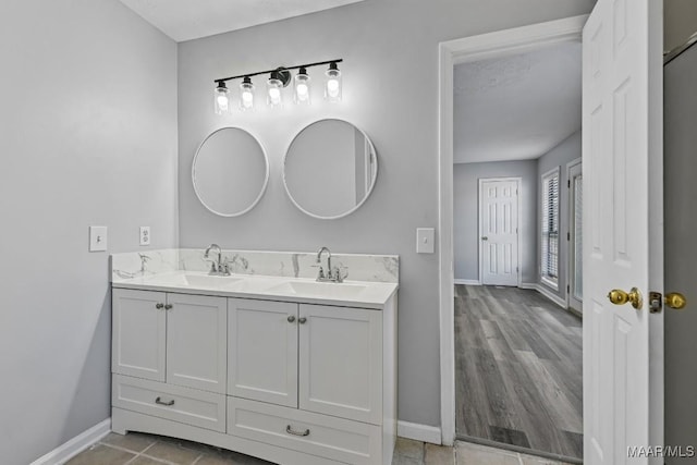 full bath featuring double vanity, a sink, and baseboards