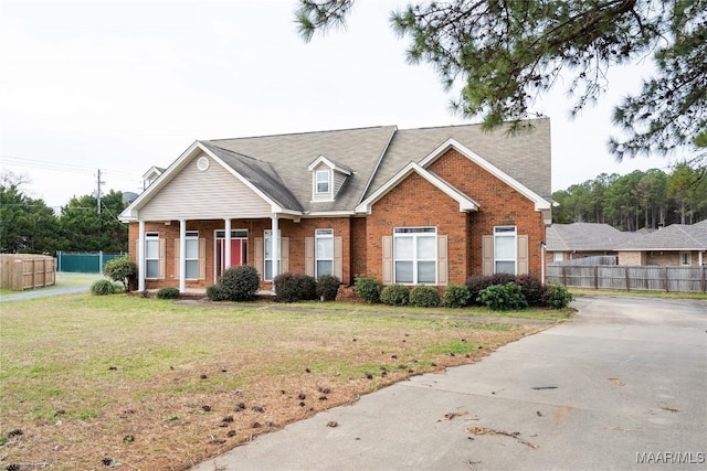 view of front of property with brick siding, fence, and a front lawn